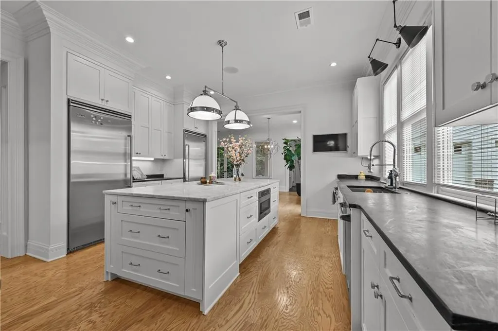 Kitchen featuring built in fridge, crown molding, a center island, white cabinets, and light wood finished floors