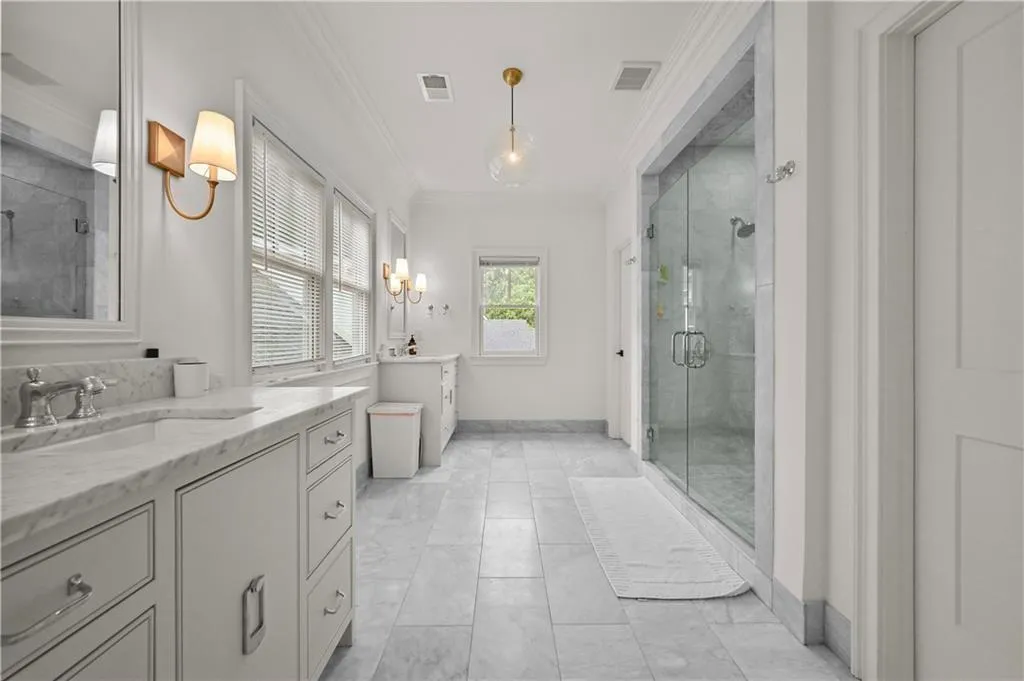Full bathroom with crown molding, a stall shower, and two vanities
