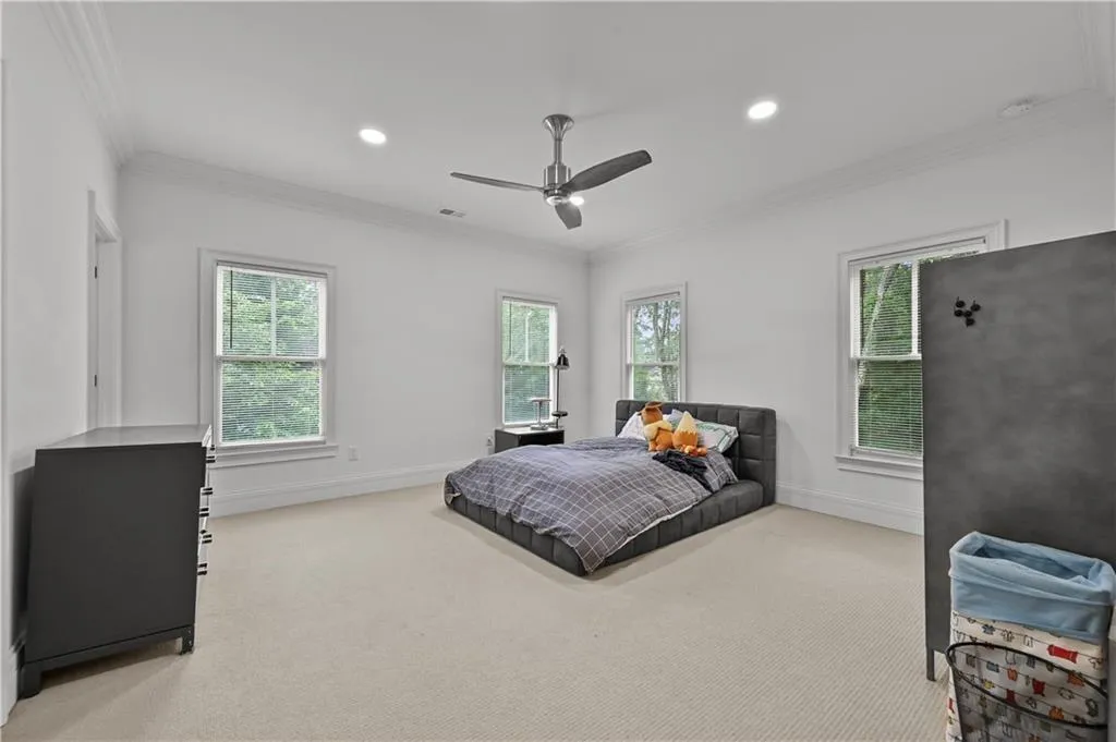 Bedroom featuring carpet, multiple windows, crown molding, recessed lighting, and a ceiling fan
