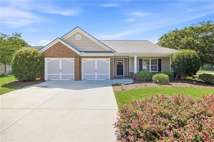 Brick and siding exterior with a two-car garage, concrete driveway, and established landscaping