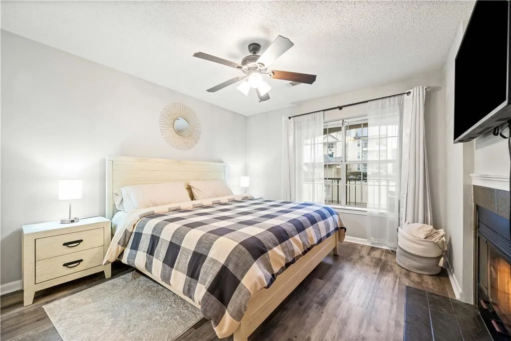 Bedroom featuring ceiling fan, dark wood-type flooring, a textured ceiling, and a fireplace