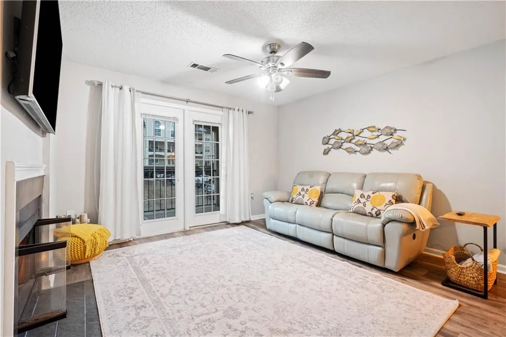 Living room featuring hardwood / wood-style flooring, ceiling fan, and a textured ceiling