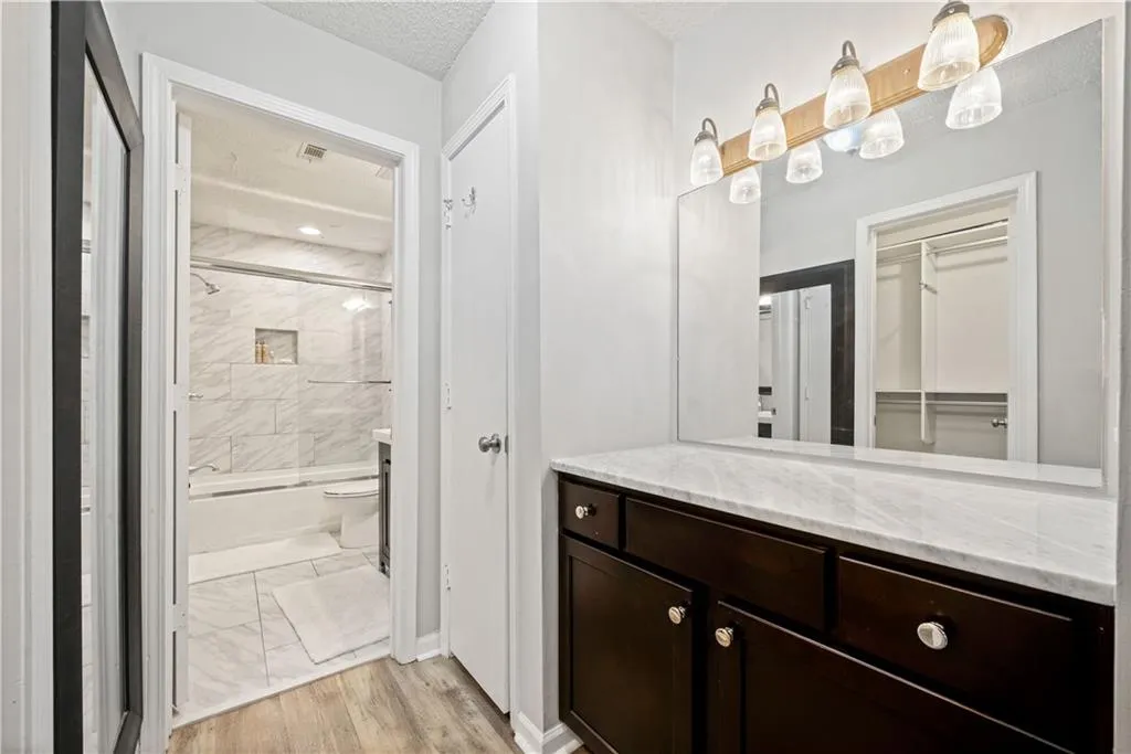 Full bathroom featuring vanity, bath / shower combo with glass door, toilet, and a textured ceiling
