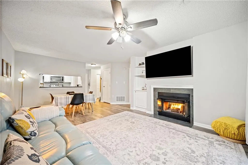 Living room with ceiling fan, hardwood / wood-style floors, and a textured ceiling