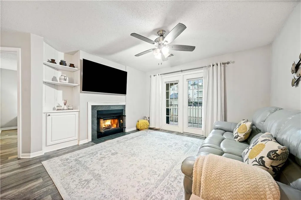 Living room with ceiling fan, a fireplace, dark hardwood / wood-style floors, and a textured ceiling