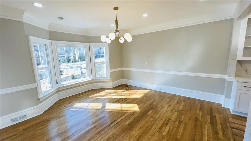 Unfurnished dining area with light wood-style floors, a chandelier, crown molding, and recessed lighting