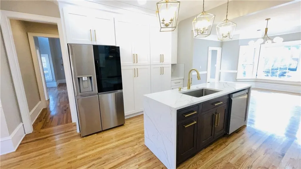 Kitchen featuring healthy amount of natural light, stainless steel appliances, white cabinets, and light stone countertops