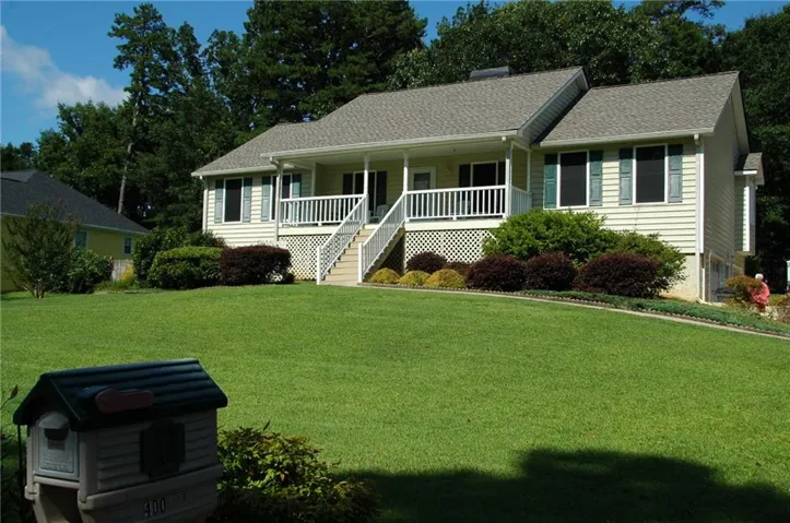 Ranch-style exterior with light-colored siding and a covered front porch featuring white railings