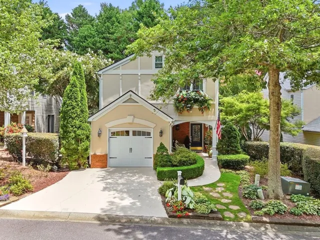 Stucco exterior featuring a single-car garage, concrete driveway, and a stone paver walkway