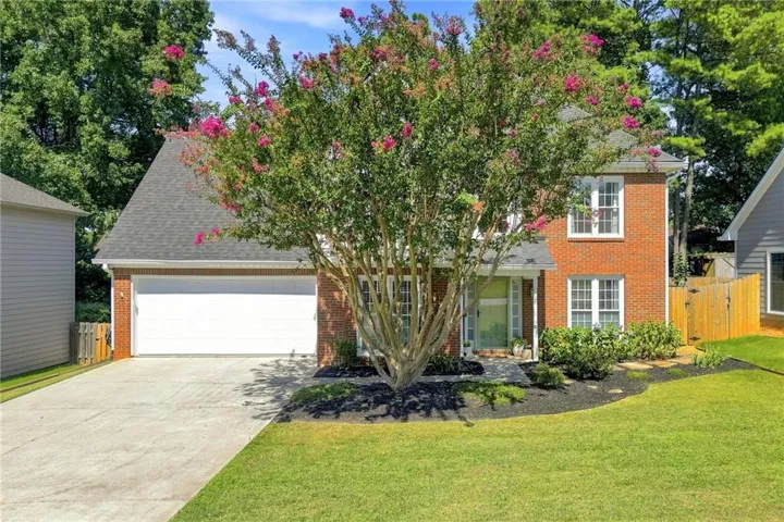 Brick exterior featuring multiple windows, a front entry, and an attached garage