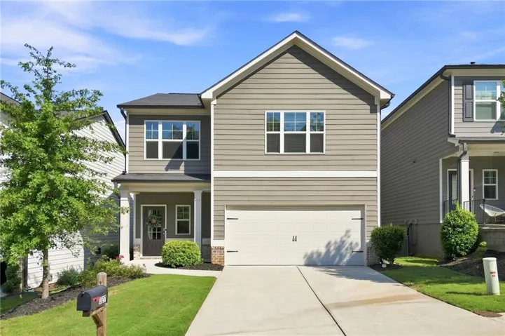 Two-story residence featuring horizontal siding, a prominent gable roof, an integrated garage, a covered front porch, and a concrete driveway