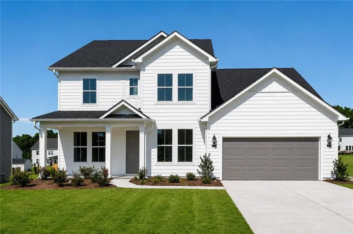 White siding exterior with a dark shingle roof, covered front porch, and an attached two-car garage