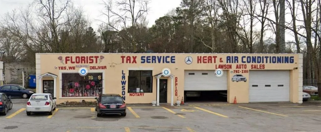 Commercial building with three distinct storefronts, two overhead garage doors, and exterior signage for multiple businesses