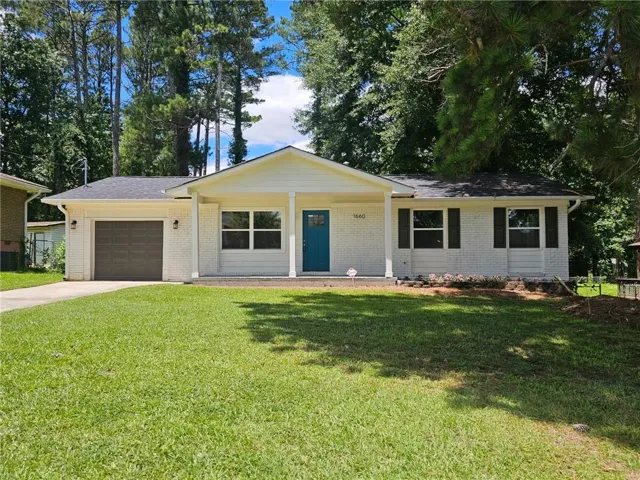 Single-story home featuring a white brick exterior and a vibrant turquoise front door