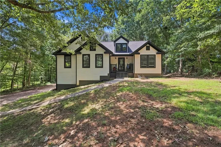 Exterior featuring light-colored siding, dark trim, and a prominent front porch