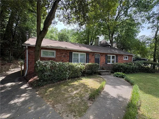 Brick exterior residence featuring a front porch with railing, dark entry door, and dark window shutters