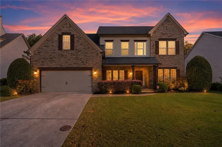 Brick and siding exterior with a covered entry, attached two-car garage, manicured lawn, and established landscaping