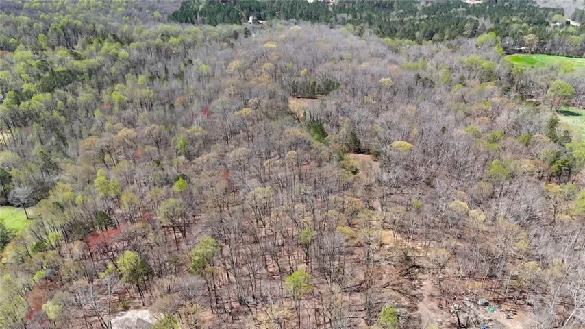 Aerial view of property and surrounding area with a forest