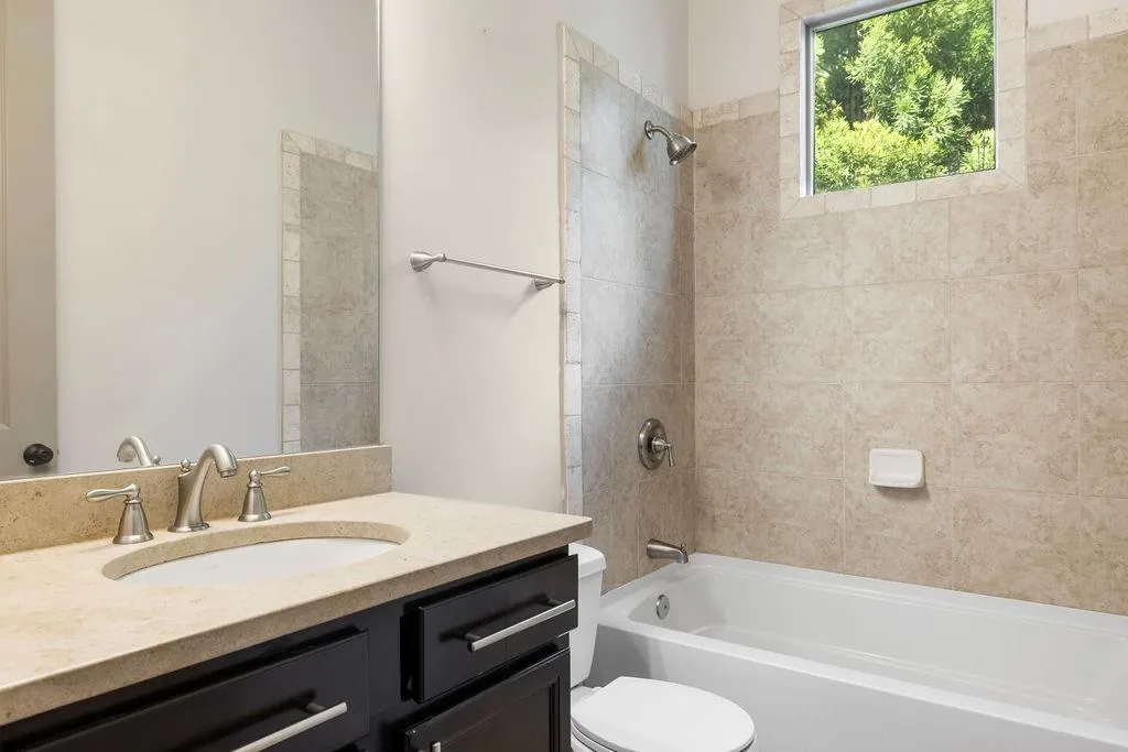 Full bathroom with toilet, vanity, and tiled shower / bath