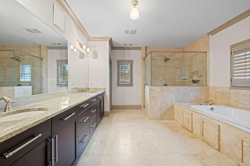Bathroom featuring double sink vanity, tile patterned floors, plenty of natural light, and separate shower and tub