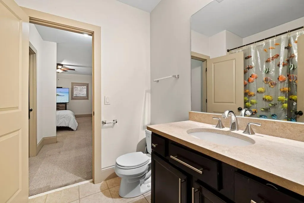 Bathroom with toilet, tile patterned floors, vanity, and ceiling fan