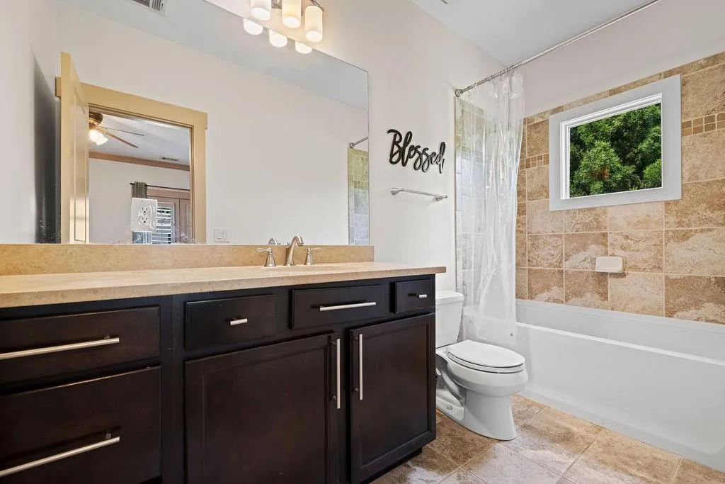 Full bathroom featuring toilet, shower / bath combo, vanity, tile patterned floors, and ceiling fan
