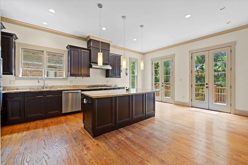 Kitchen with french doors, pendant lighting, stainless steel dishwasher, a center island, and light hardwood / wood-style floors