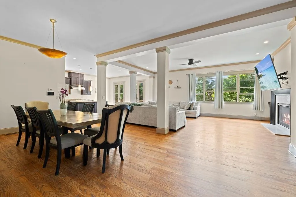 Dining room featuring light wood-type flooring, decorative columns, a high end fireplace, and ceiling fan