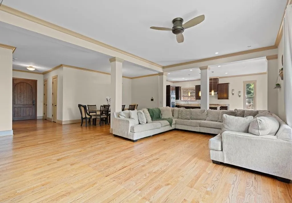 Living room featuring ceiling fan, decorative columns, light hardwood / wood-style flooring, and ornamental molding