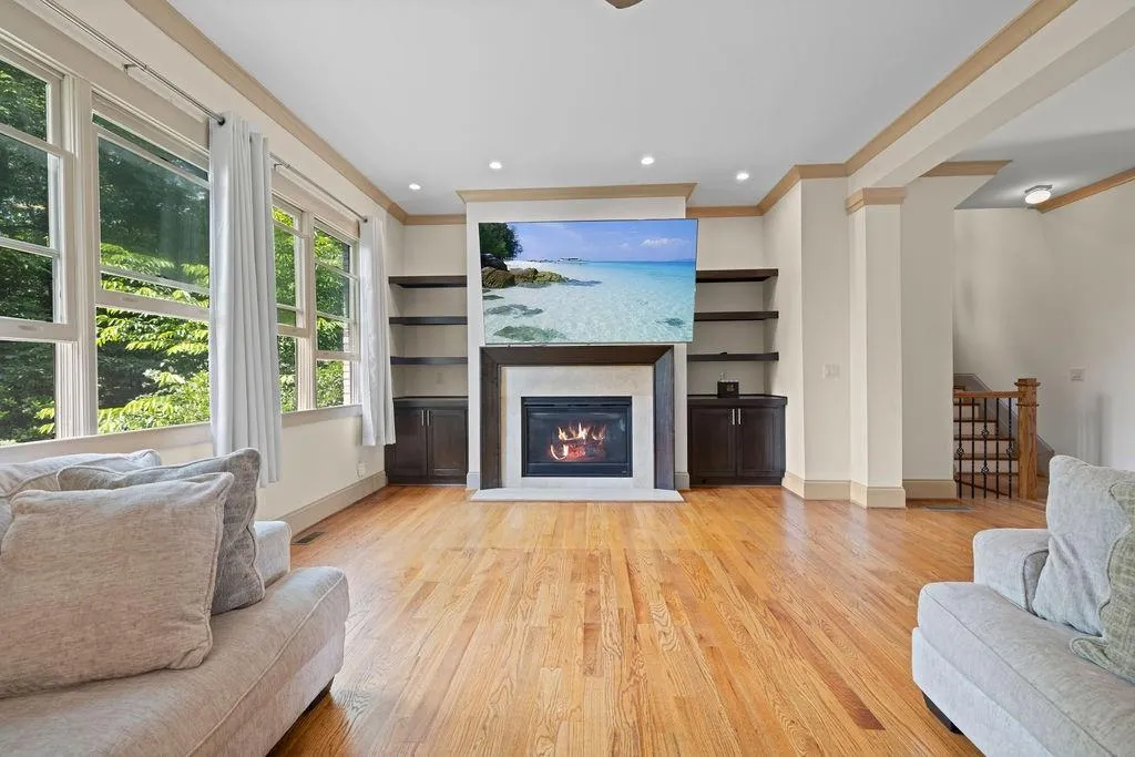 Living room with crown molding, built in features, and light hardwood / wood-style floors
