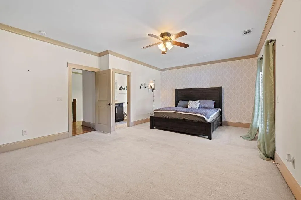 Carpeted bedroom featuring ceiling fan and crown molding