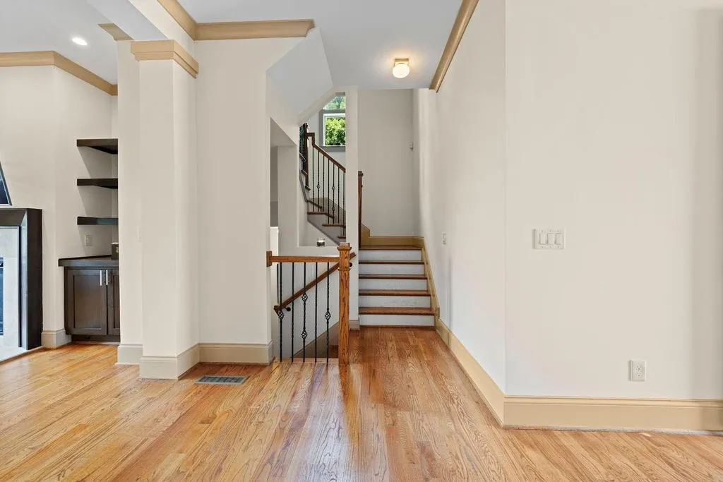 Staircase with hardwood / wood-style flooring and crown molding
