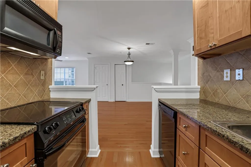 Kitchen with backsplash, black appliances, brown cabinetry, and light wood finished floors