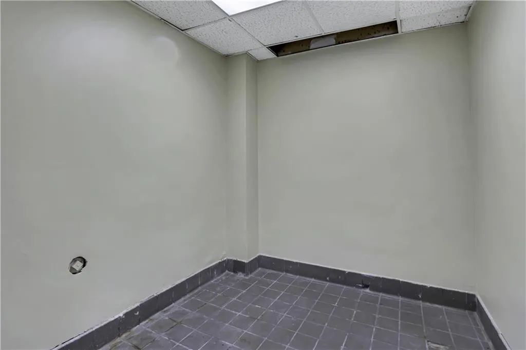 Empty room featuring a drop ceiling and dark tile patterned floors