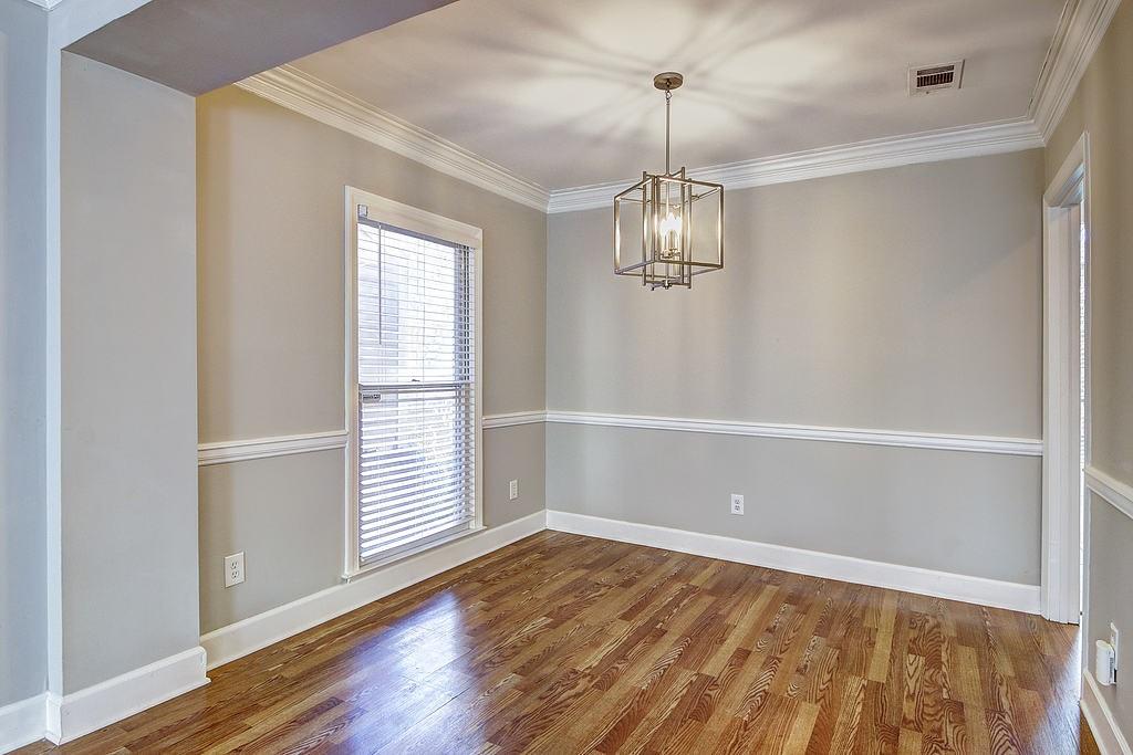 Spare room with ornamental molding, an inviting chandelier, and dark wood-type flooring