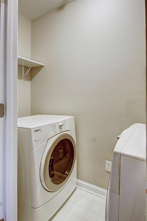 Clothes washing area featuring washer and dryer and light tile flooring