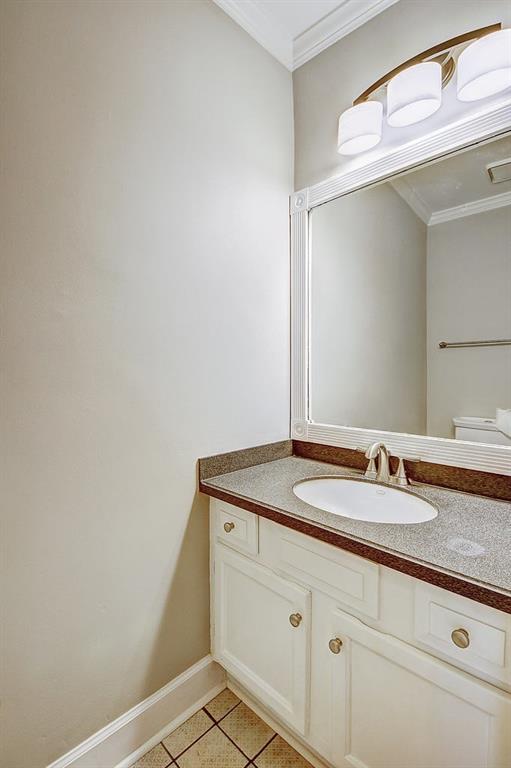 Bathroom featuring crown molding, tile floors, vanity, and toilet