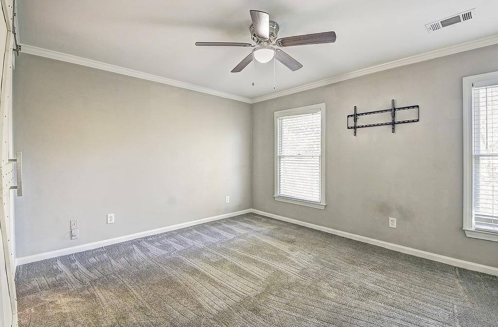 Unfurnished room with a healthy amount of sunlight, crown molding, dark carpet, and ceiling fan