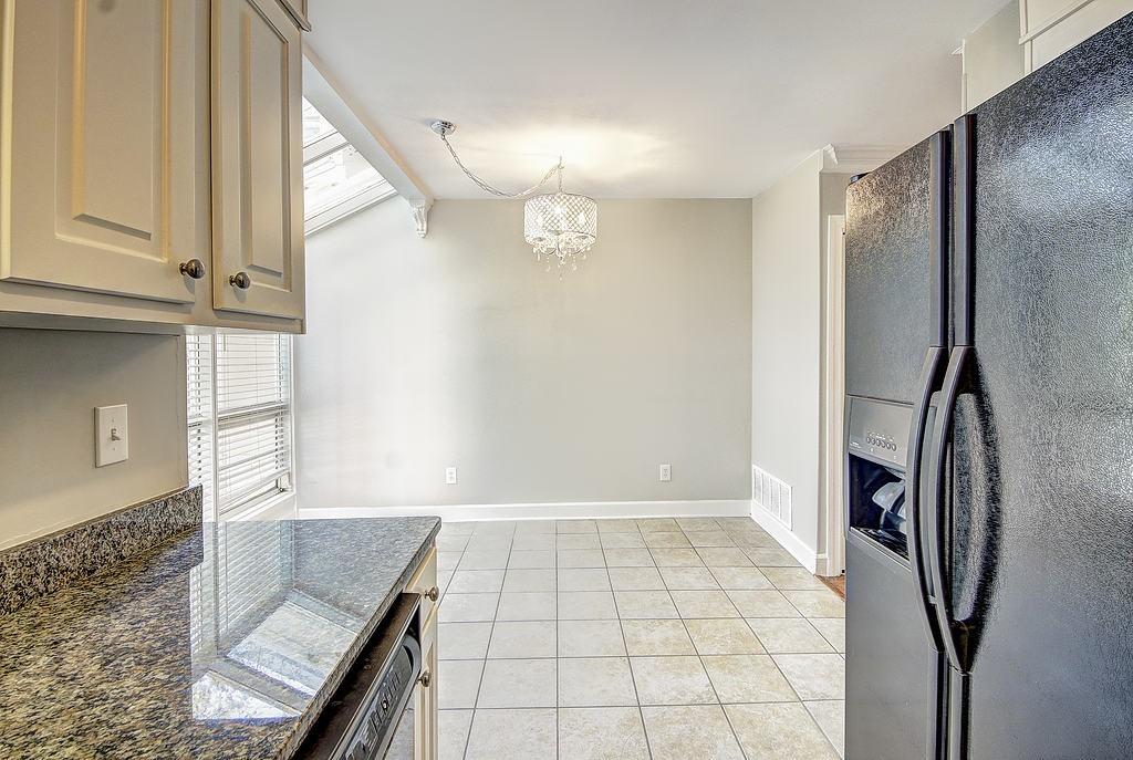 Kitchen with refrigerator with ice dispenser, a chandelier, beamed ceiling, pendant lighting, and light tile floors