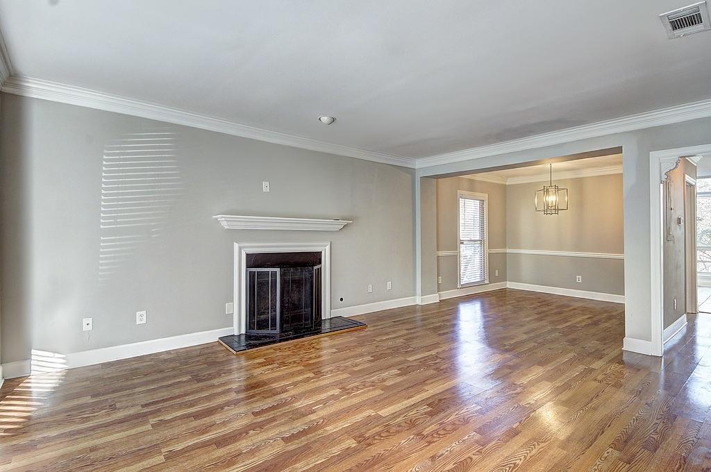 Unfurnished living room with ornamental molding, a notable chandelier, and hardwood / wood-style flooring