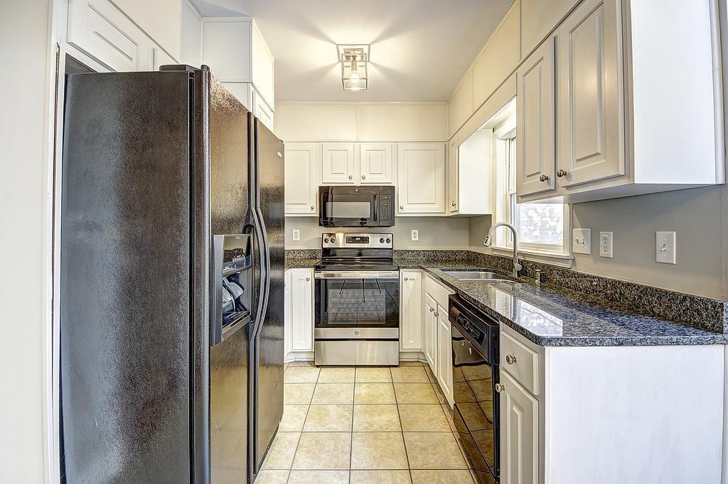 Kitchen with sink, white cabinetry, light tile floors, and black appliances