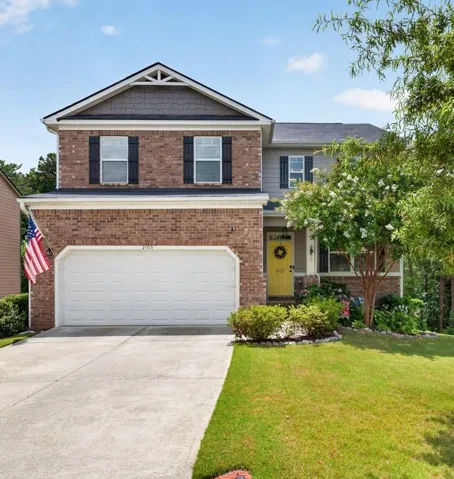 Brick and siding exterior featuring a two-car garage, concrete driveway, and a front entry with a vibrant yellow door
