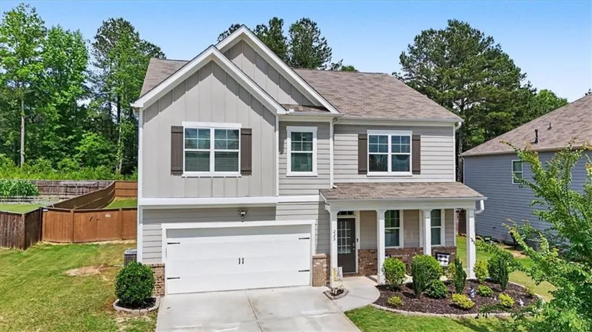 Two-story exterior with light gray siding and brown shutters, featuring a covered front porch with white columns