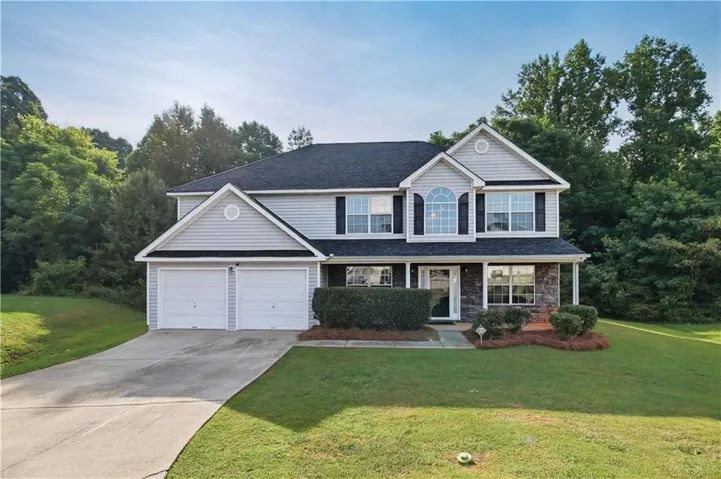 Two-story residence featuring light gray siding with dark stone accents