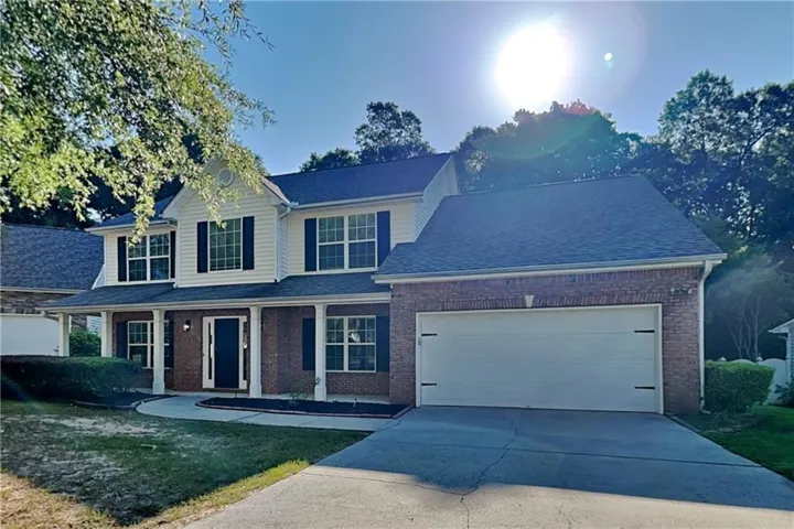 Brick and siding exterior with a covered porch, attached two-car garage, and established landscaping
