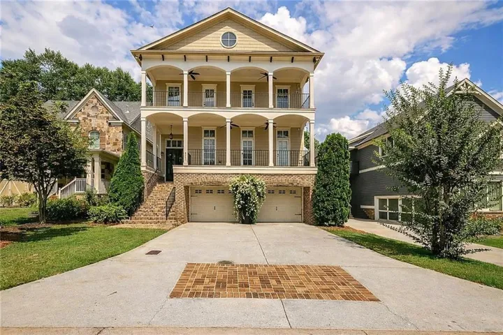Two-story residence featuring a ground-level garage, elevated main entrance, and double-tiered covered balconies with decorative railings