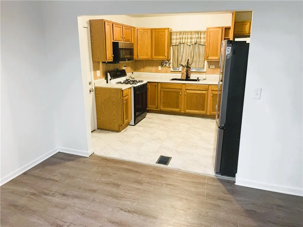 Kitchen featuring light countertops, appliances with stainless steel finishes, brown cabinets, light wood finished floors, and tasteful backsplash