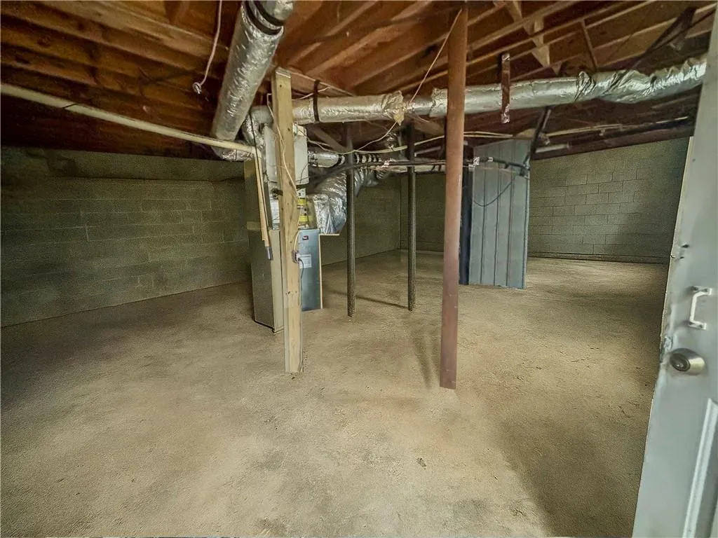 Unfinished below grade area featuring heating unit