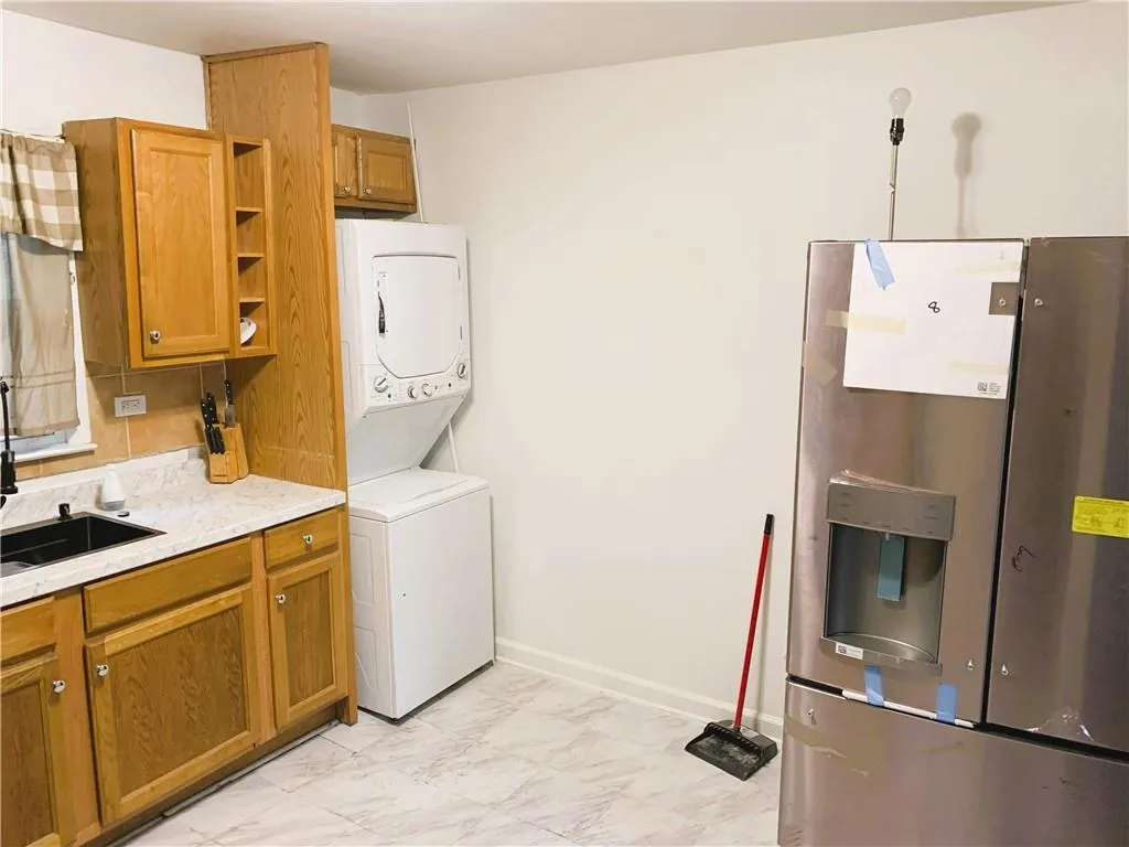 Laundry area featuring light marble finish flooring and stacked washer and clothes dryer
