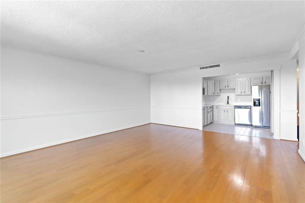 Unfurnished living room with light wood-style flooring, a textured ceiling, and crown molding